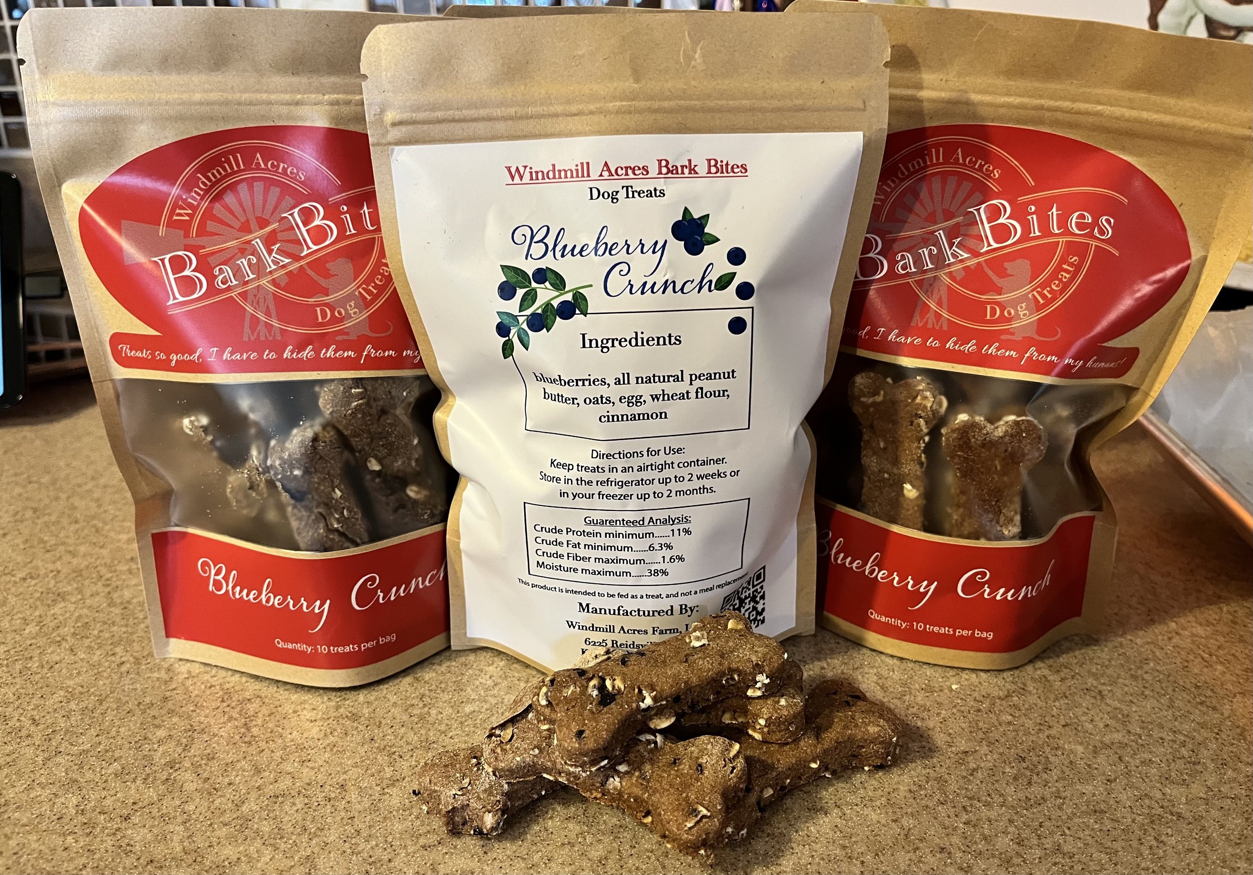 Bark Bites Blueberry Crunch dog treats displayed in eco-friendly packaging, featuring ingredients like blueberries, peanut butter, oats, and cinnamon. The image showcases the treats' bone shape and highlights the product's natural and healthy qualities for dogs.